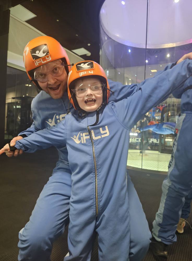 Two people in indoor skydiving gear posing for a photo.